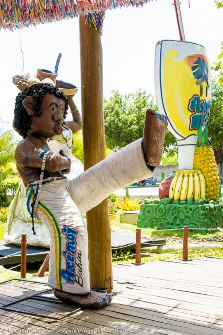 Imagem de um boneco com roupa de capoeira na Praia de Taperapuan.